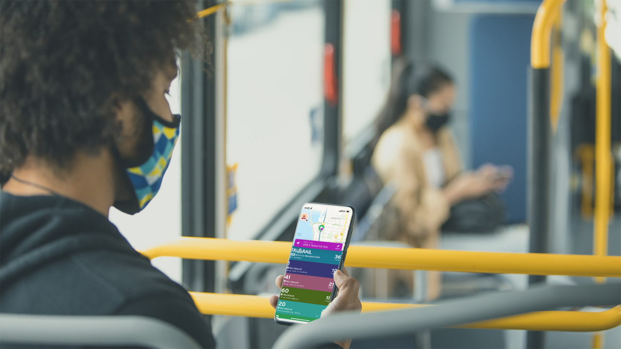 Young commuter reviews Transit app information on her smartphone while sitting on the bus.