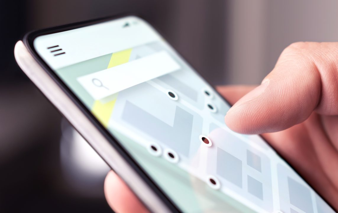 Man searching for trip planning information on a close-up view of his smartphone.